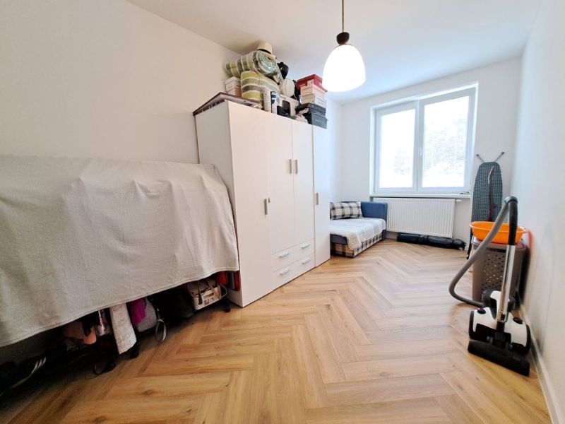 Ein Zimmer in einer 3-Zimmer-Wohnung mit einem Boden in Holzoptik, einem Schrank und einem Staubsauger.