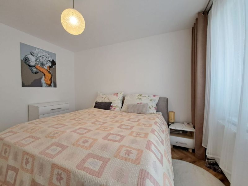 Schlafzimmer mit hellem Bett und Nachttischen in einer 3-Zimmer-Wohnung mit Wanddekoration.