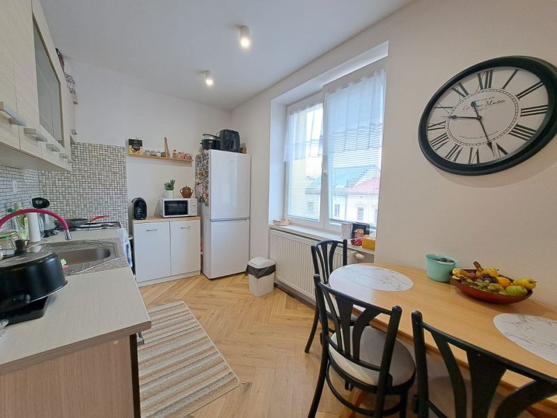 Küche in einer 3-Zimmer-Wohnung mit Holzboden, Esstisch und großer Uhr.