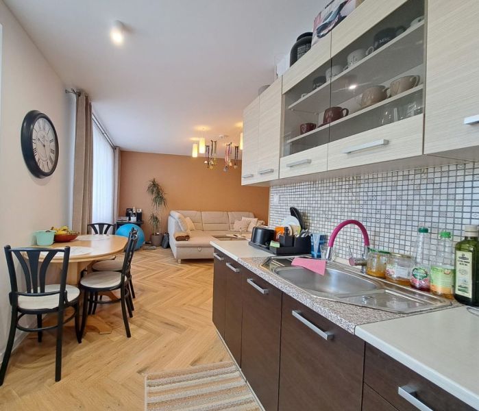 Küche mit Essecke in einer 3-Zimmer-Wohnung, Boden mit Holzdekor, Sofa.