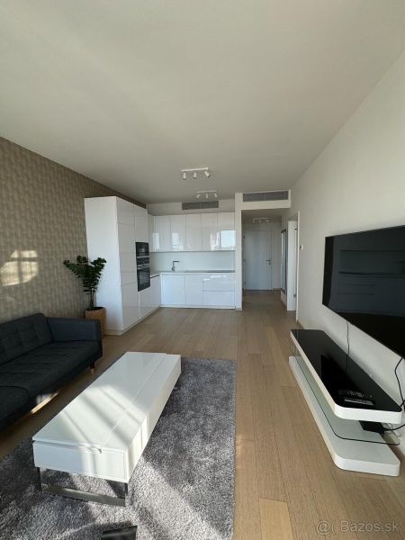 Wohnzimmer in einer 2-Zimmer-Wohnung mit Küche, Sofa und Holzboden.