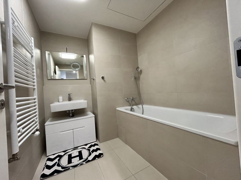 Badezimmer in einer 2-Zimmer-Wohnung mit Badewanne, Waschbecken und Wandspiegel.