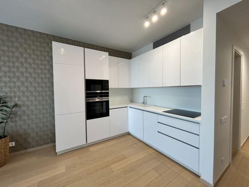Küche in einer 2-Zimmer-Wohnung mit Holzboden und eingebauten Geräten.