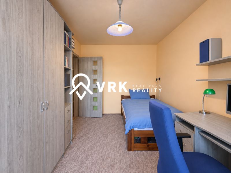 Ein Zimmer in einer 3-Zimmer-Wohnung mit einem Bett, einem Schrank, einem Tisch und einem blauen Sessel.