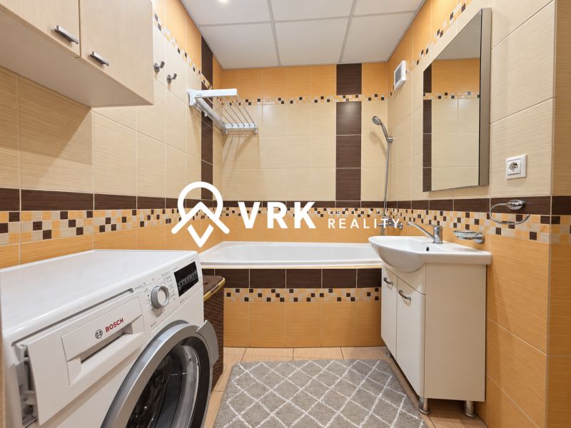Badezimmer in einer 3-Zimmer-Wohnung mit Fliesen in warmen Farbtönen und einer Bosch-Waschmaschine.