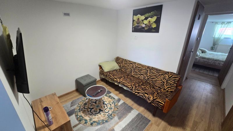 Wohnzimmer in einem Einfamilienhaus mit Holzboden, Sofa und Fernseher.