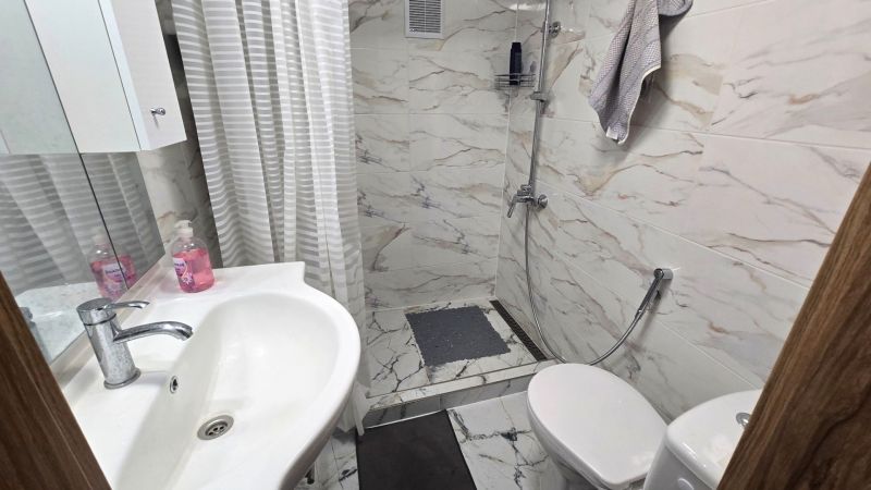 Badezimmer in einem Einfamilienhaus mit Waschbecken, Dusche und Fliesen mit Marmordekor.