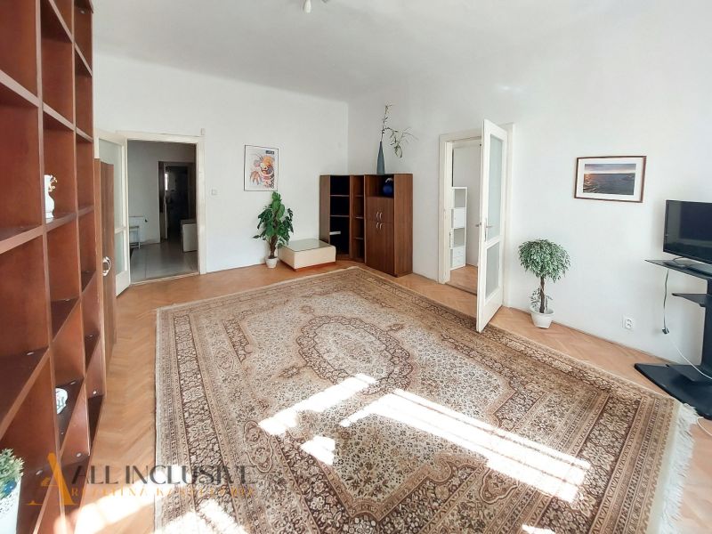 Ein helles Wohnzimmer mit Holzboden, Teppich und Möbeln in einer Zweizimmerwohnung.