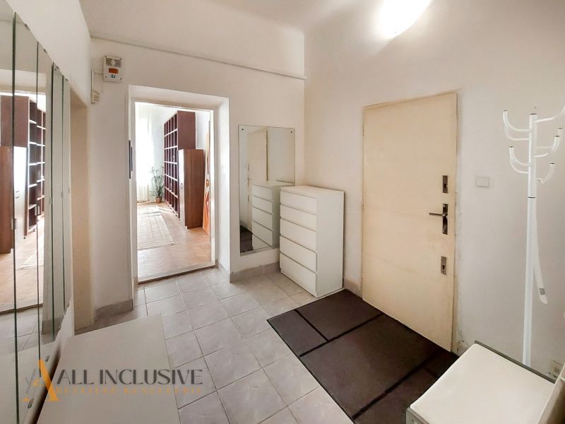 Flur mit weißen Möbeln, Spiegel und Eingang zum Zimmer in einer 2-Zimmer-Wohnung.