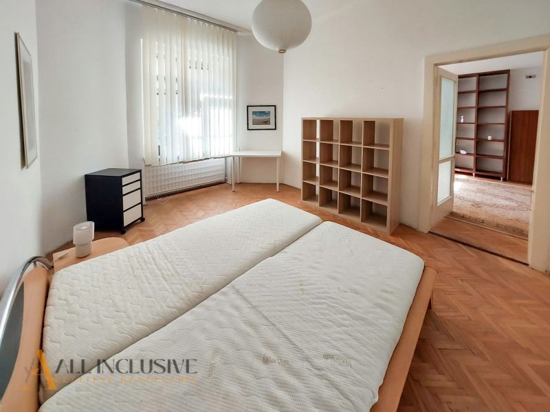 Schlafzimmer mit Einbauregal, Schreibtisch und Boden in Holzoptik in einer 2-Zimmer-Wohnung.