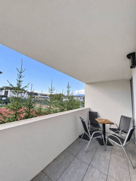 Balkon einer 2-Zimmer-Wohnung mit Sitzgelegenheit, Blick ins Grüne und modernem Fliesenboden.