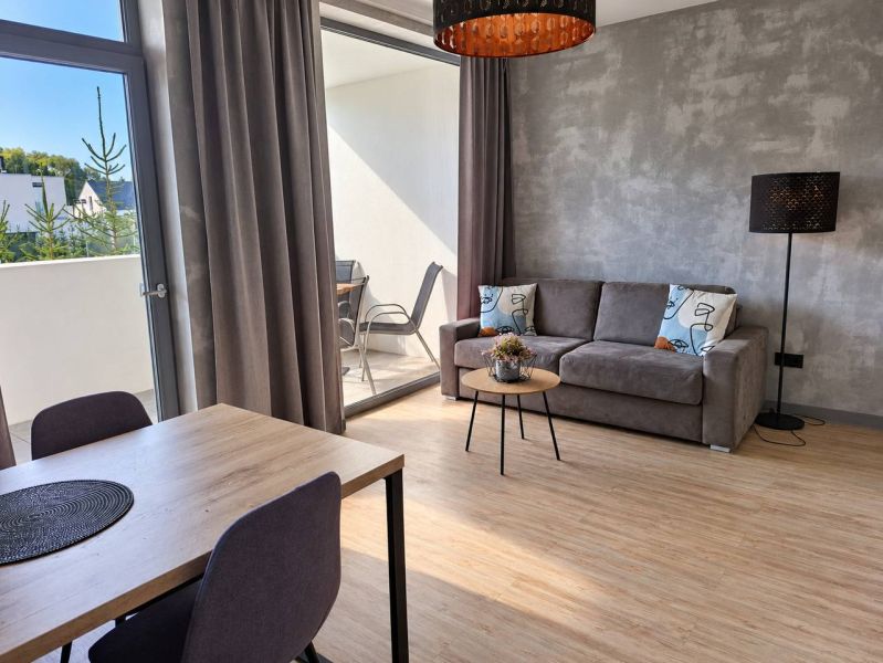 Wohnzimmer in einer 2-Zimmer-Wohnung mit Holzboden und Balkon.