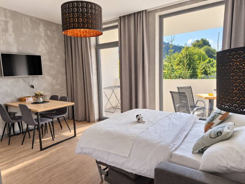 Ein Zimmer in einer 2-Zimmer-Wohnung mit einem Holzboden, einem Esstisch und einem Bett.