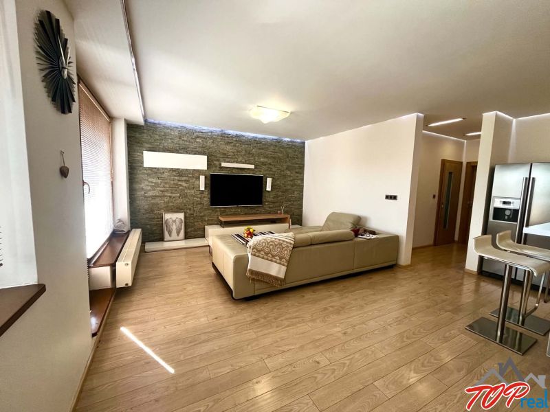 Wohnzimmer in einer 3-Zimmer-Wohnung mit Holzboden, Fernseher und Sofa.