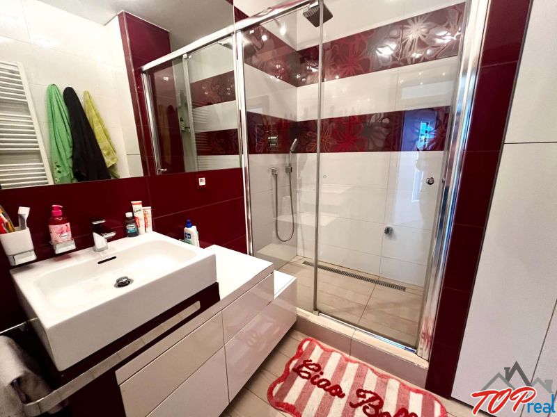 Badezimmer mit Duschkabine und Waschbecken in einer 3-Zimmer-Wohnung mit dekorativen Fliesen.