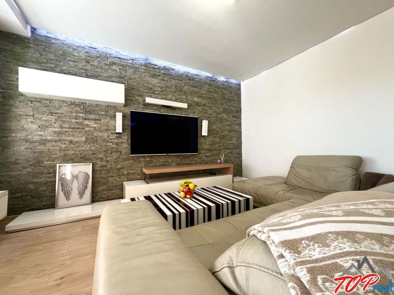 Wohnzimmer in einer 3-Zimmer-Wohnung mit Ledersofa und Holzboden.