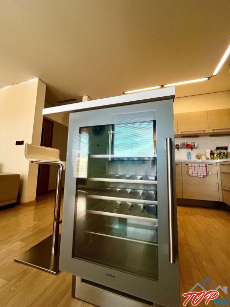 Küche in einer 3-Zimmer-Wohnung mit einem Weinkühlschrank und einem Boden in Holzoptik.