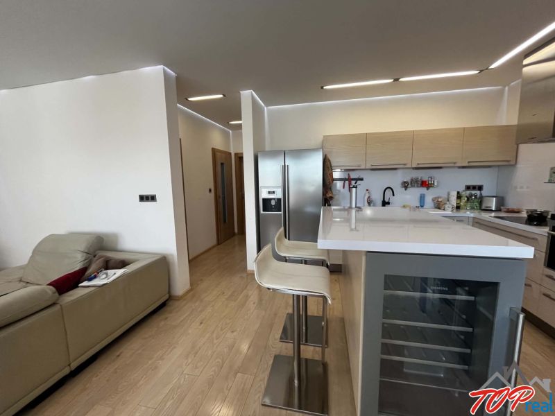 Küche in einer 3-Zimmer-Wohnung mit Bartheke und Boden in Holzoptik.
