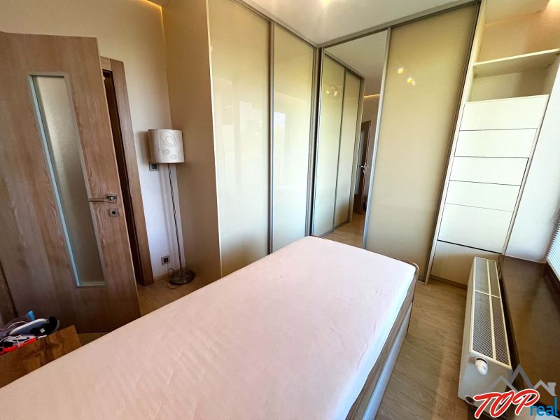 Schlafzimmer in einer 3-Zimmer-Wohnung mit Holzboden, Bett und Einbauschrank.