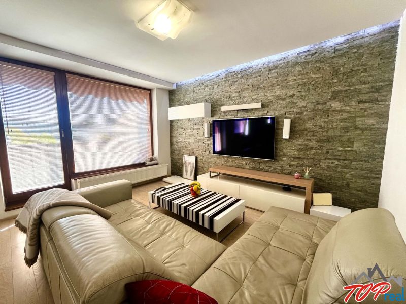 Wohnzimmer in einer 3-Zimmer-Wohnung mit Ledersofa, Steinwand und Holzboden.
