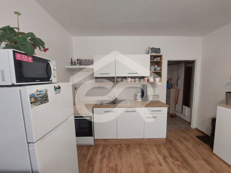 Küche in einem Einzimmerapartment mit Mikrowelle, Kühlschrank und Holzboden.