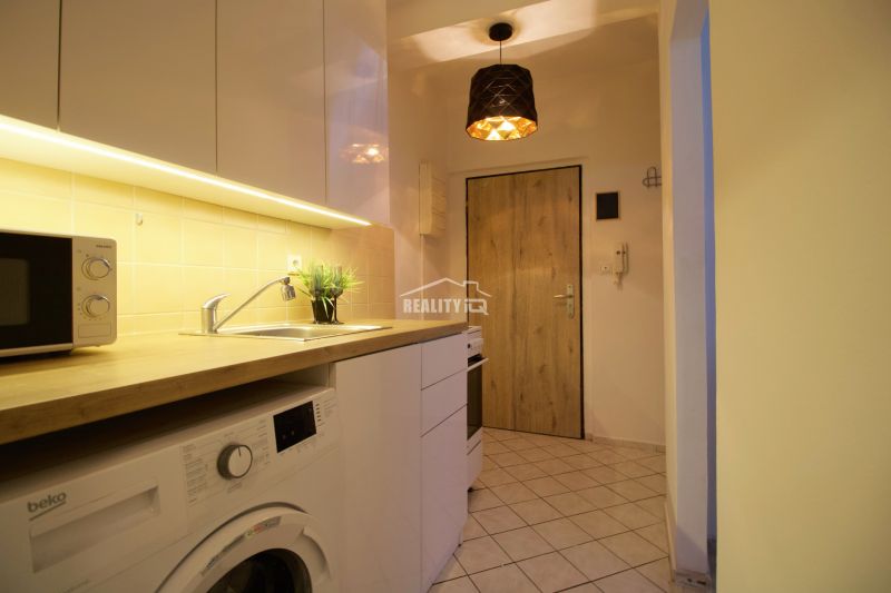 Kochnische in einem Studio-Apartment mit Holzboden und weißen Schränken.