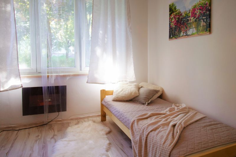 Einzimmerwohnung mit Bett, Decke und Fenster, neben einer Theke in Holzdekor.