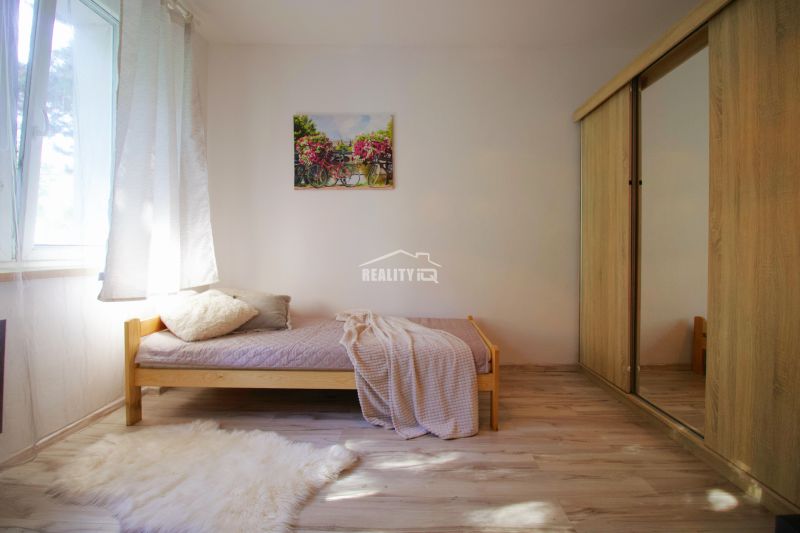Einzimmerwohnung mit einfachem Bett, Kleiderschrank und Boden mit Holzdekor.
