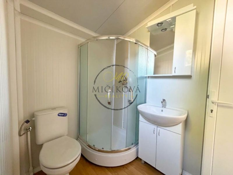 Badezimmer mit Dusche, Waschbecken und Boden mit Holzdekor. Besondere Immobilien.
