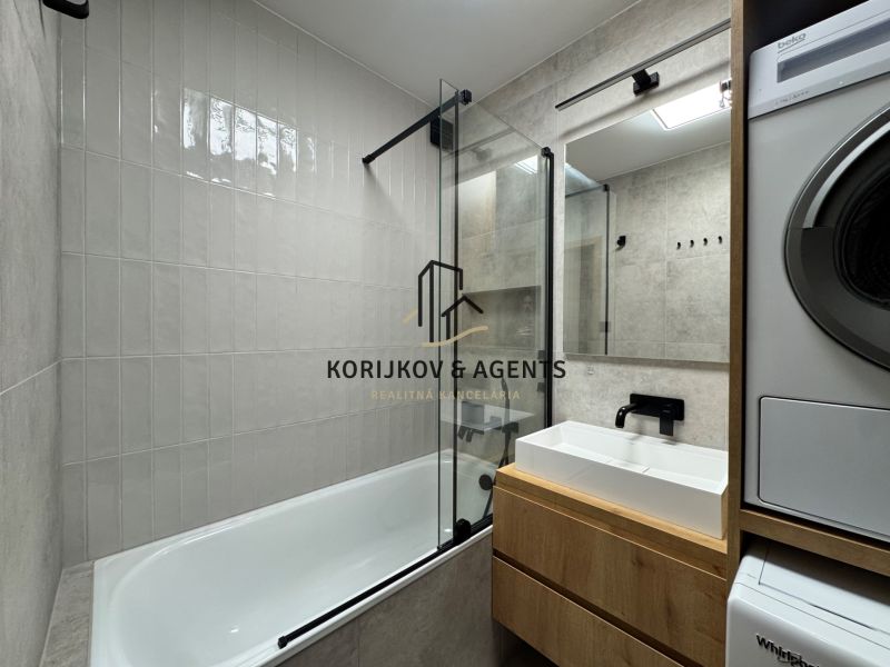 Modernes Badezimmer in einer 3-Zimmer-Wohnung mit Badewanne, Waschbecken und Waschmaschine.