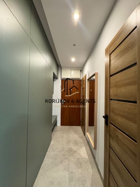 Flur in einer 3-Zimmer-Wohnung mit Holzboden und Holztüren.