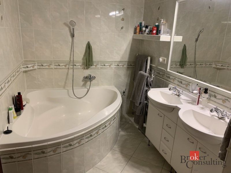 Badezimmer mit Eckbadewanne, Doppelwaschbecken und Keramikfliesen in einer 3-Zimmer-Wohnung.