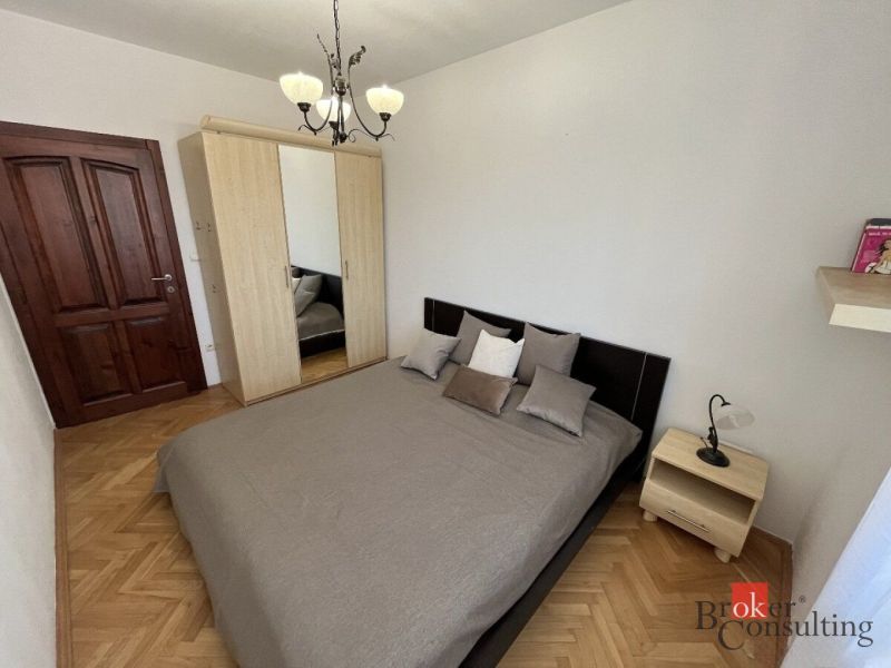 Schlafzimmer in einer 3-Zimmer-Wohnung mit einem Doppelbett und einem Schrank, Boden mit Holzdekor.