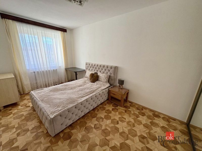 Schlafzimmer mit Bett, Nachttisch und Boden in Holzoptik, 3-Zimmer-Wohnung.