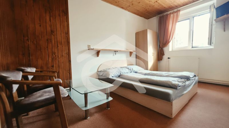 Schlafzimmer der Ferienwohnung mit Doppelbett, Sesseln und Fenster, Boden mit Holzdekor.