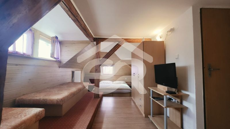 Innenraum einer Ferienwohnung mit Bett, Fernseher und Holzboden.