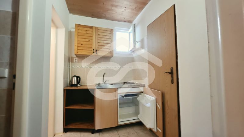 Küchenzeile im Ferienapartment mit Holzschränken, Spüle und Minikühlschrank.