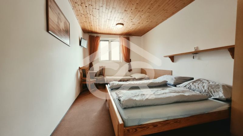 Schlafzimmer im Ferienapartment mit zwei Betten und Fernseher, Boden mit Holzdekor.