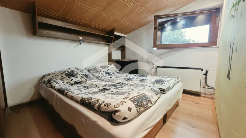 Dachgeschoss-Schlafzimmer mit Doppelbett, Regal und Fenster, Ferienwohnung.