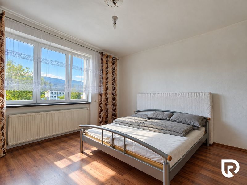 Schlafzimmer im Einfamilienhaus mit Bett und Boden in Holzoptik.