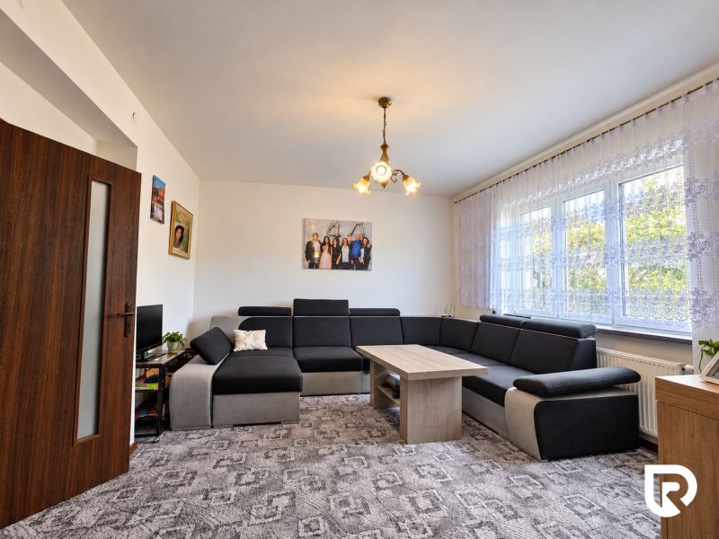 Wohnzimmer in einem Einfamilienhaus mit großem Sofa und auffälligem Teppich.