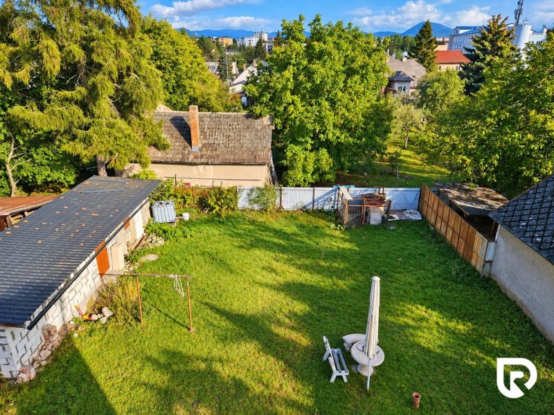 Der Garten eines Einfamilienhauses in Martin mit Rasen und sichtbaren Dächern der nahegelegenen Gebäude.