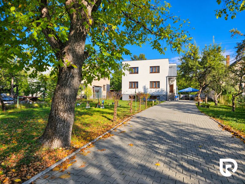 Ein Einfamilienhaus in Martin mit Garten, Bäumen und gepflastertem Gehweg.