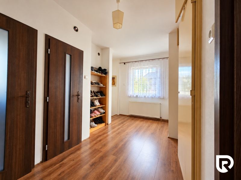 Innenraum eines Einfamilienhauses mit Holzboden, Türen und einem Schuhregal.