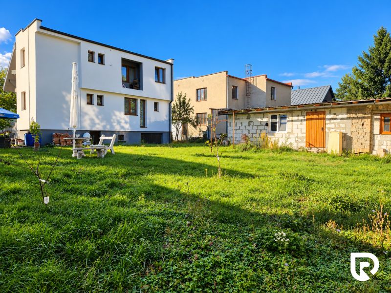 Ein Einfamilienhaus in Martin mit Garten, Terrasse und einem angrenzenden Gebäude auf einem geräumigen Grundstück.