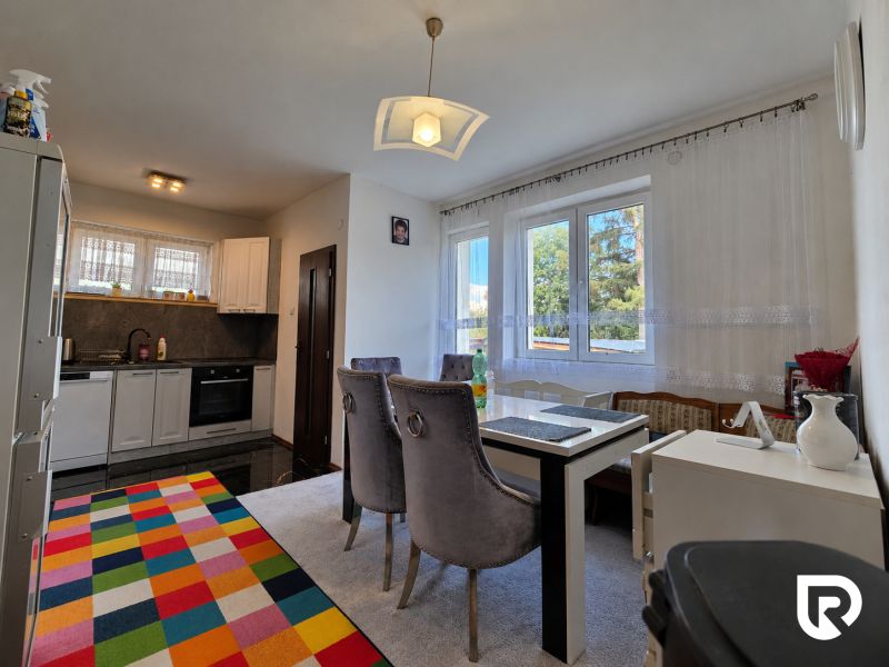 Küche mit Esszimmer in einem Einfamilienhaus, Boden mit Holzdekor, bunter Teppich.