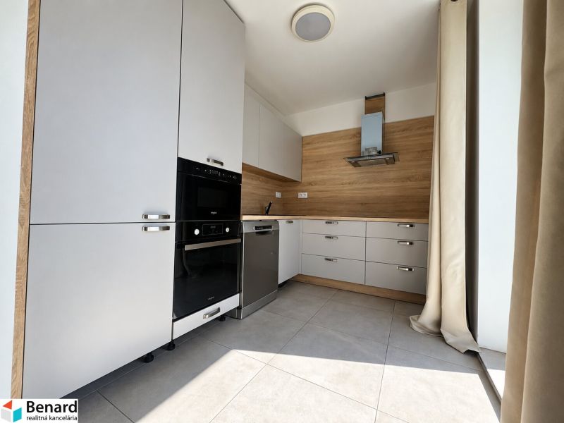 Küchenzeile in einer 2-Zimmer-Wohnung, helle Elemente, Boden mit Holzdekor, eingebaute Geräte.