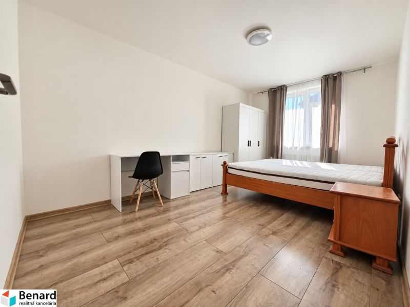 Ein Zimmer in einer 2-Zimmer-Wohnung mit einem Bett, einem Tisch und einem Boden in Holzoptik.
