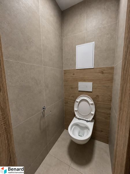 WC mit Keramikfliesen und Boden in Holzoptik in einer 2-Zimmer-Wohnung.