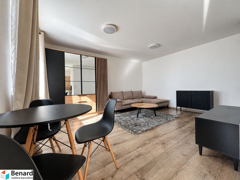Wohnzimmer in einer Zweizimmerwohnung mit Holzboden, schwarzen Möbeln und einem Sofa.